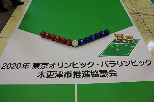 2020年東京オリンピック・パラリンピック木更津市推進協議会と書かれ、中央に白いボール、両脇に赤と青のボールが並べられ、「ボッチャきさポン」が描かれたボッチャコートの写真
