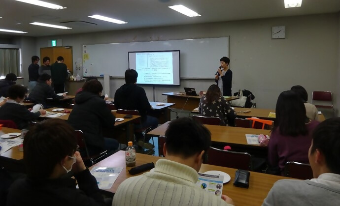 部屋の前で講師の方が話しています。