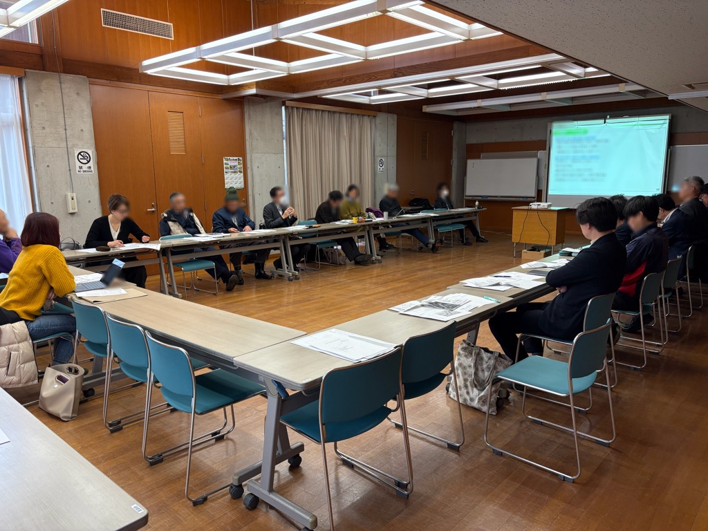 第2回里山再生部会の会議開催中の様子で、前方のモニターの前にコの字に机が並び、委員が座っている