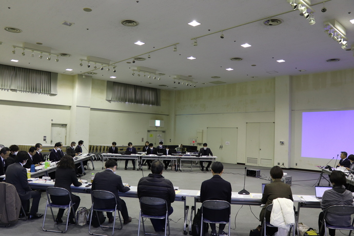 モニターを軸に半円状に机が並び、委員が座っている
