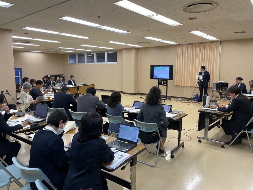 第1回資源循環部会の会議開催中の様子 モニターを軸に半円状に机が並び、委員が座っている