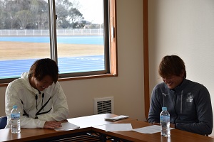 L字型に設置された長机の席に座る吉田眞紀人選手とカレン・ロバート選手が笑顔で対談している様子の写真