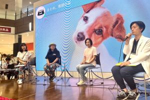 大型スクリーンに犬の画像が映るステージで、4人の登壇者が椅子に座ってトークショーの写真