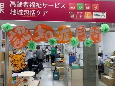 高齢者福祉課の窓口に「アルツハイマー月間」と書かれた透明アクリル板が設置され、奥では職員の方々が仕事をしている様子の写真