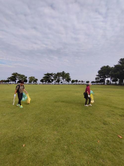 潮浜公園公園内の芝生を副市長及び職員がゴミ袋をもって清掃する様子
