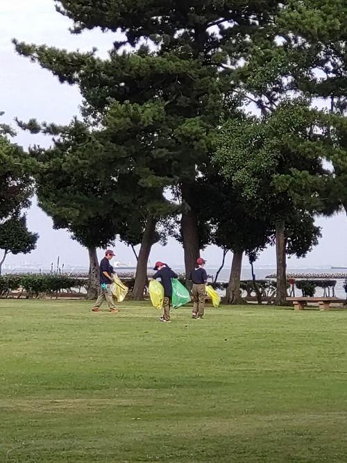 潮浜公園公園内の芝生を一般ボランティアの方がゴミ袋をもって清掃する様子