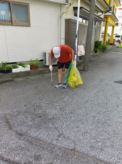 鳥居崎海浜公園近くの道路を市長がゴミ袋をもって清掃する様子