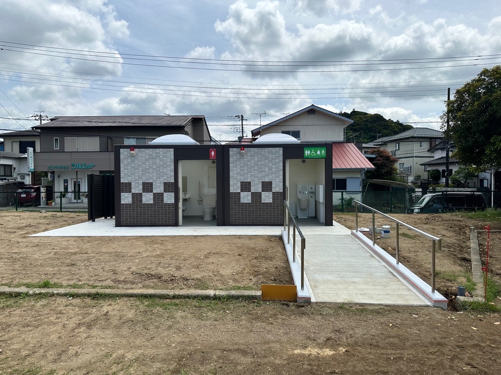左側に女性、右側に男性のマークの書かれた公衆トイレがあり、右側にスロープがある写真
