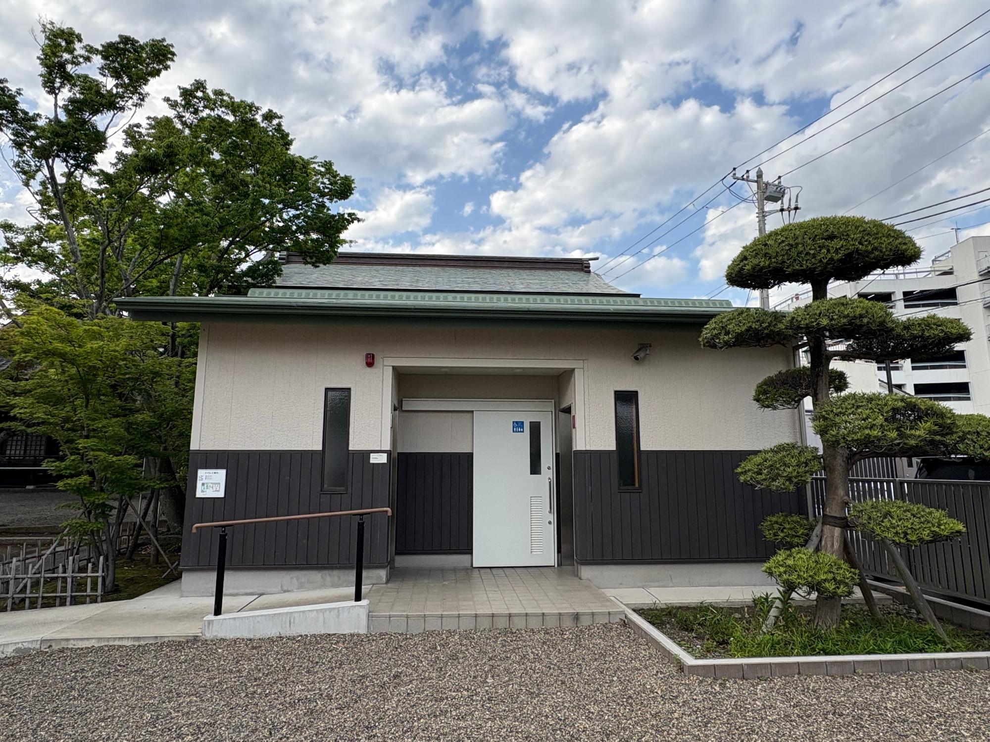 松の木の間に公衆トイレの建物がある写真
