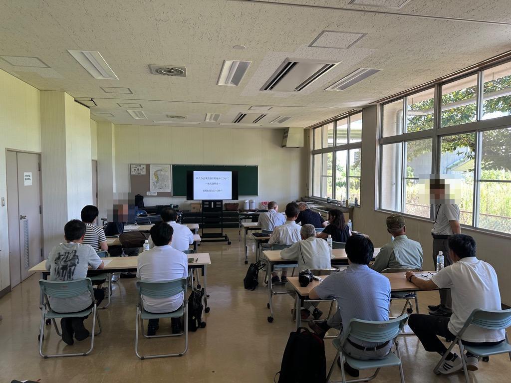 会議室で出席者がモニターに向かって座っている画像