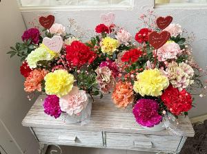 赤やピンク、黄色のカーネーションなど色とりどりの花をたくさん使用したフラワーアレンジメントの写真