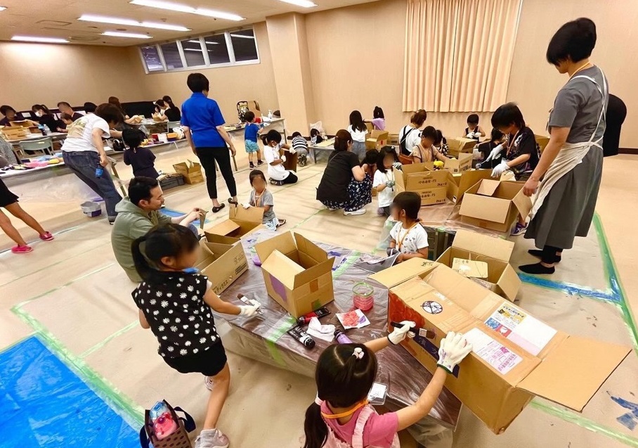 段ボールを使って工作をしているこどもと保護者。