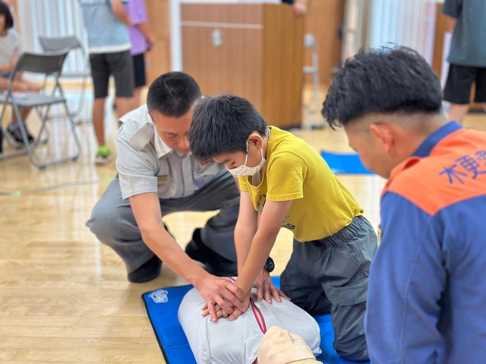 消防職員の指導のもと、心肺蘇生法を人形で実践している子どもの画像