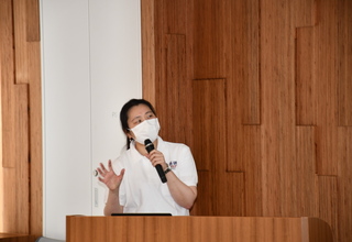 白シャツを着た女性講師が講演をしている様子をアップで撮影した写真