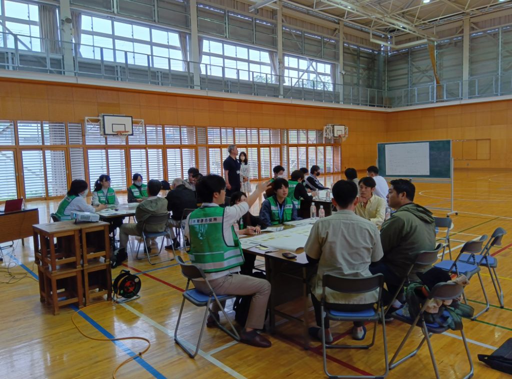 市の職員と地域の方々とが机を囲んで避難所開設について議論をする様子
