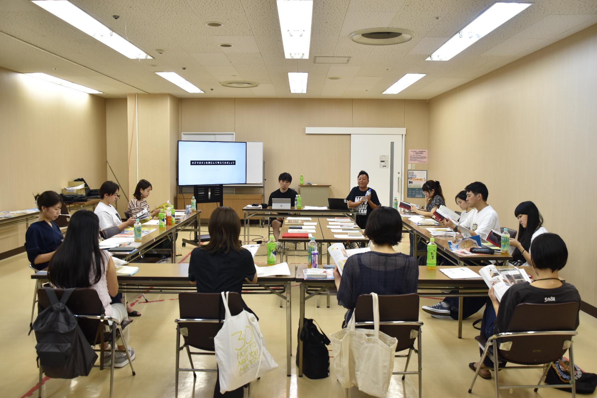 会議室の中で市民ライター11名がコの字型に座っており、講師が部屋の一番前で話をしている様子