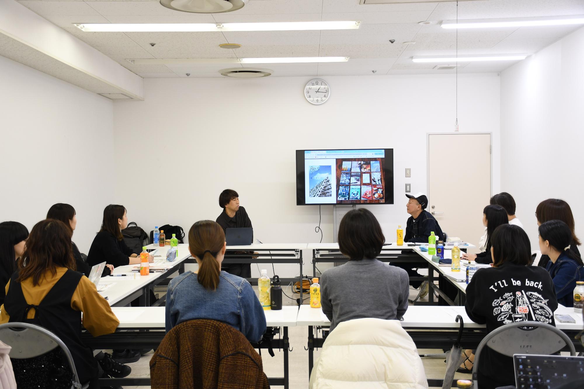 会議室の中で市民ライター11名がコの字型に座っており、講師が部屋の一番前で話をしている様子