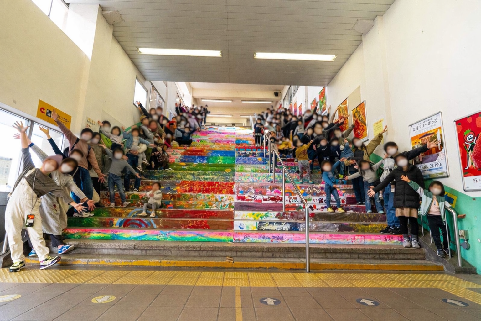 階段アートの前でみんなが手を広げて集合写真を撮っている様子