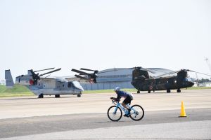 陸上自衛隊木更津駐屯地の滑走路を走るバイクと、自衛隊航空機の写真