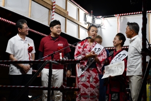「やっさいもっさい踊り大会」の表彰式で本部ステージにて、「泉水きもの教室＆拓大紅陵」連の代表者2名が優勝の証書を掲げ、渡辺市長を始めとする審査員3名が囲んでいる写真