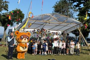 会場のステージ前に並ぶ、渡辺市長と本市マスコットキャラクター「きさポン」と子どもたちの写真