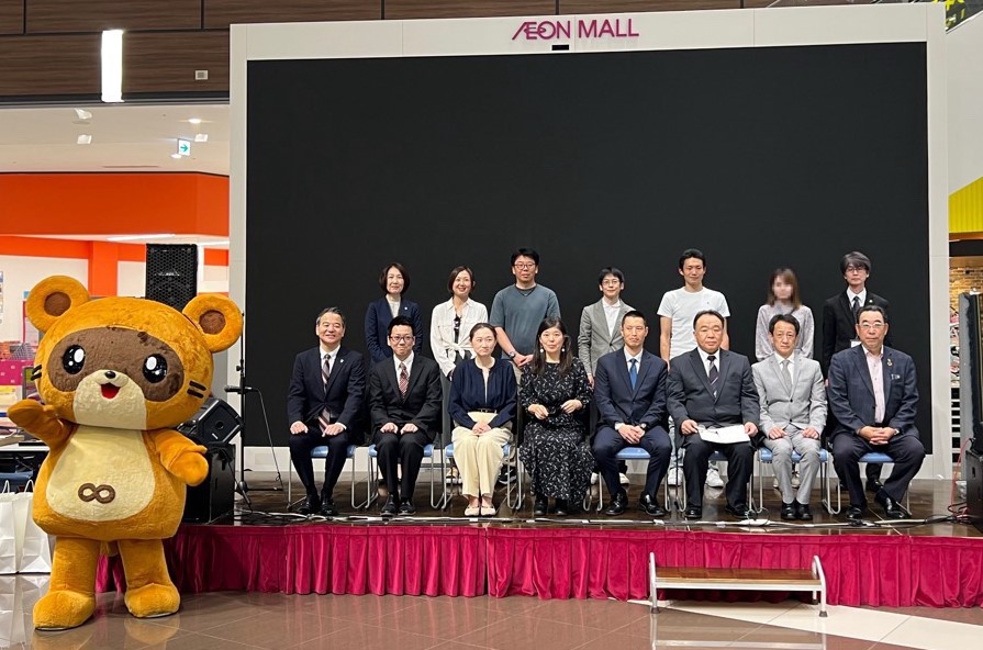 表彰式での集合写真(ステージ下の左端に、きさポン、ステージ上の前列左から、あいおいニッセイ同和損害保険株式会社 千葉支店長 桶本様、個人の部第3位、第2位、第1位、グループの部第1位、AD千葉支店プロ会 石井様、ステージ上の後列左から木更津市 鈴木市民協働部長、グループの部第3位,第2位、個人の部第4位、第5位、木更津市 亀田教育部次長)