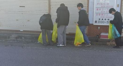 鳥居崎海浜公園近くの道路を清和大学生徒の方がゴミ袋をもって清掃する様子