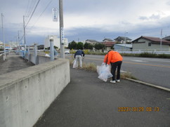 道路沿いにある花壇のような場所でゴミを拾っている2名の参加者の写真