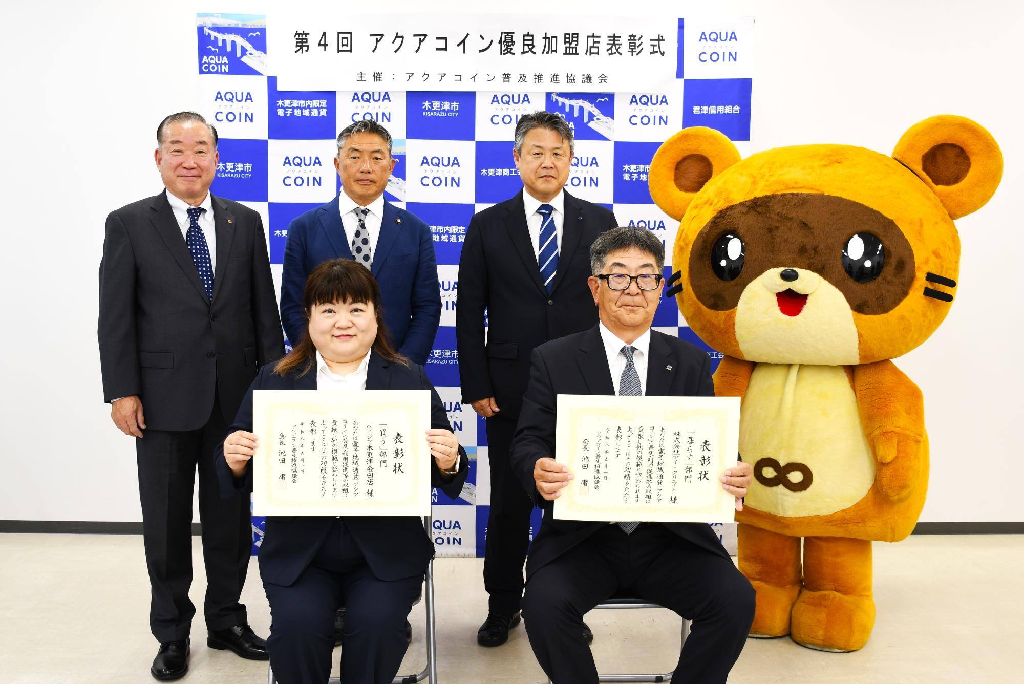 第4回アクアコイン優良加盟店表彰式の記念写真。後列左から池田会長、渡辺副会長、平野副会長、きさポン。前列左からベイシア木更津金田店、株式会社アイ・クリエイト