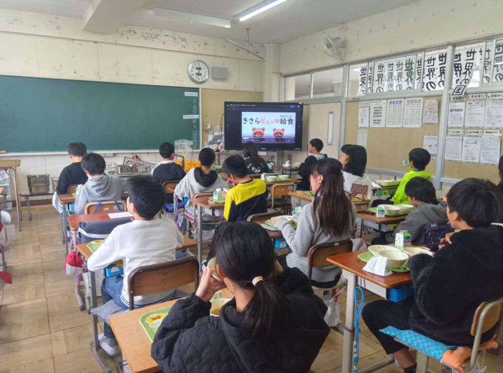 子ども達が給食を食べながら動画を視聴している写真