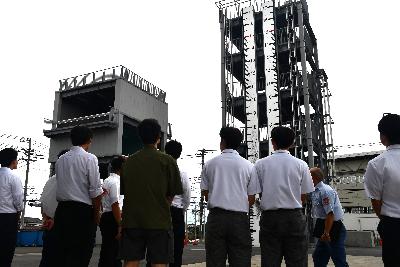 前回就職説明会でのスーツ姿の参加者が15メートルの高さの訓練施設を見上げている様子