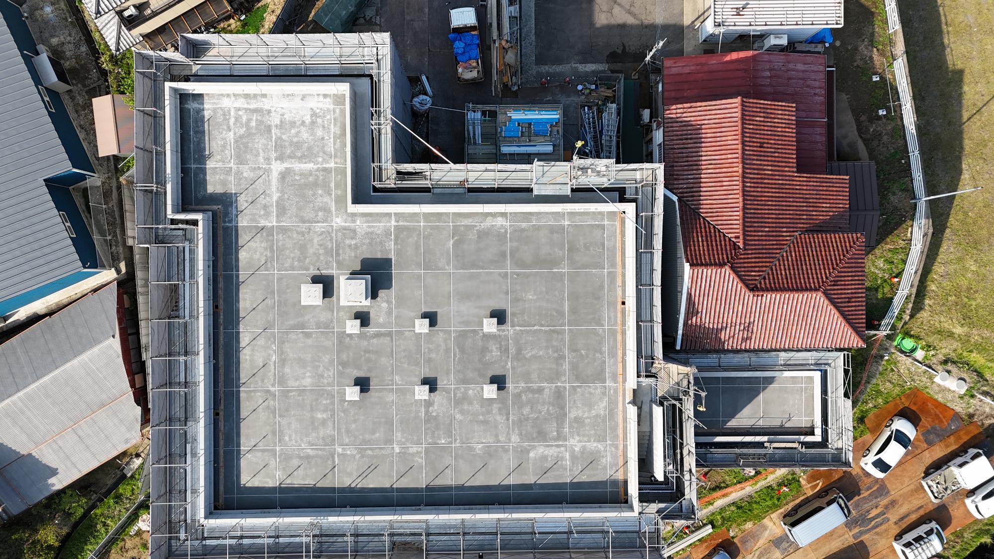 令和8年4月16日時点の建設工事の状況をドローンで建設建物の真上から撮影。太陽光発電設備の基礎が6か所設置されている他、無線設備の基礎が2か所設置されている。庁舎右側には発電機室の工事が行われている。