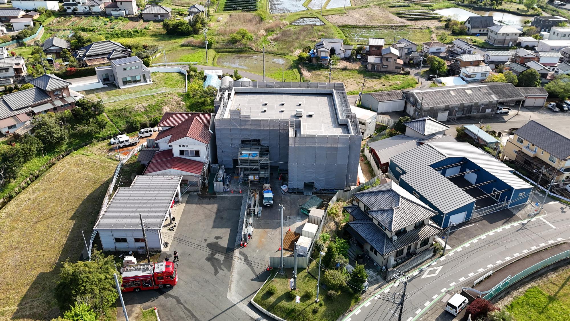 令和8年4月16日時点の工事の状況をドローンで上空から富来田分署敷地全体を撮影した写真。建設中の建物には仮囲いが設置されており、外観は確認できない状況の写真