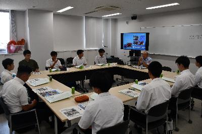 前回就職説明会でのスーツ姿の参加者が職員の説明を真剣に聞いている様子