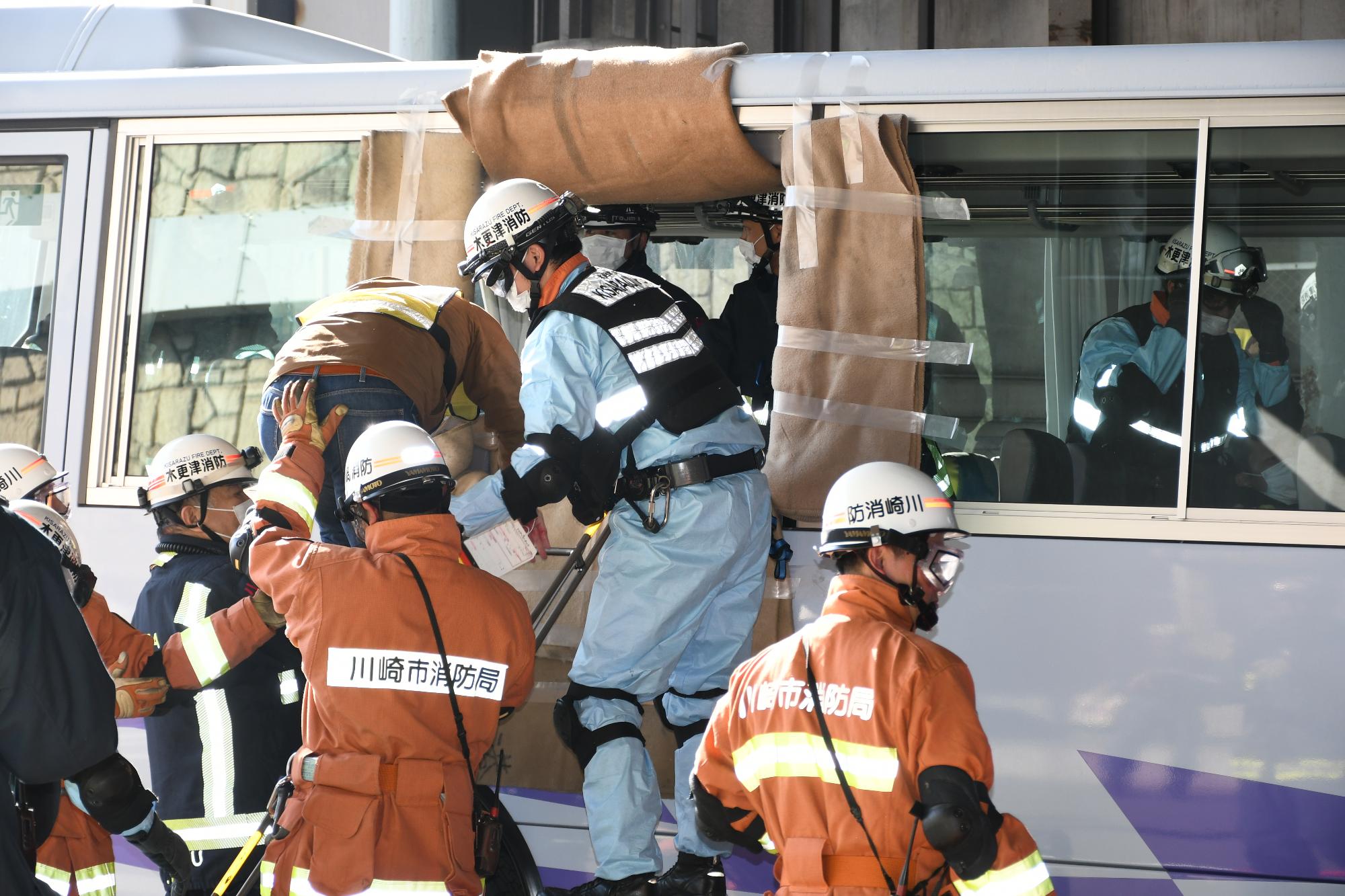 訓練会場であるトンネル内で、消防隊員4名が訓練事故車両である大型バスからバス内にいた歩行可能な傷病者を窓から梯子をかけ窓から救出している様子