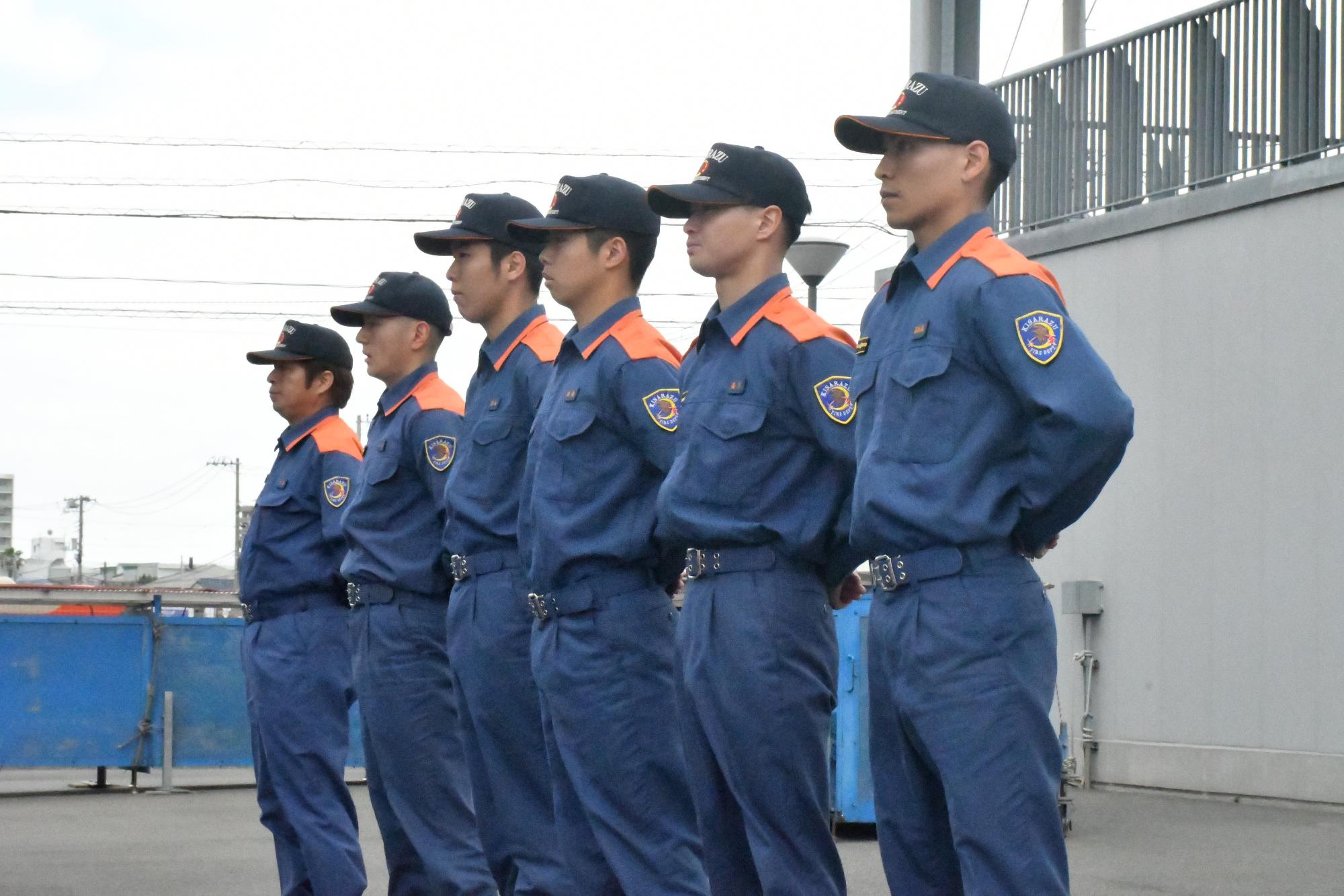 横一列に並んだ活動服を着用した上席者2名及び4名の新規採用職員が正面を向いている様子の写真