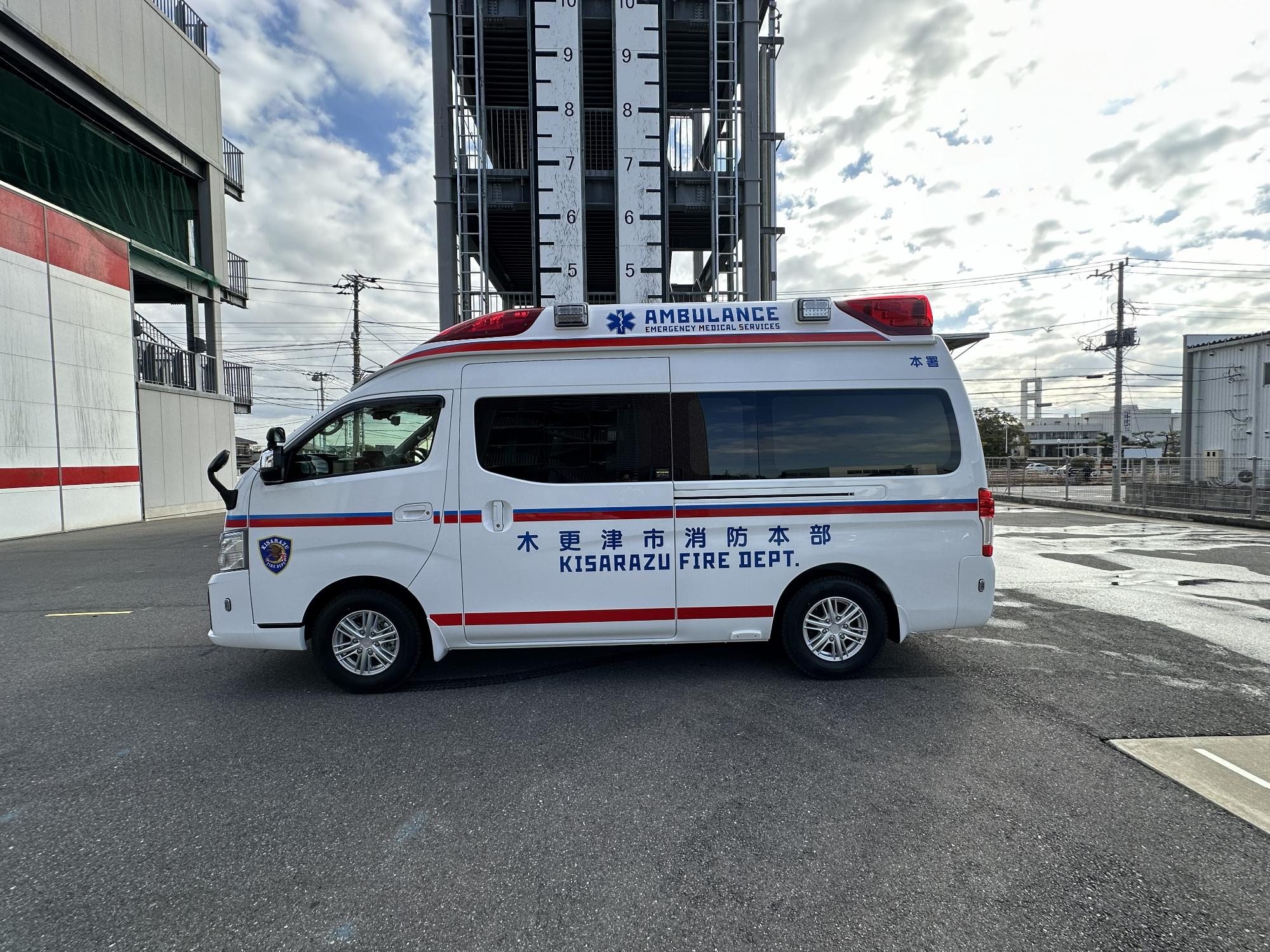 青空の下消防本部敷地内で令和7年度に更新した救急車の左側を撮影した写真