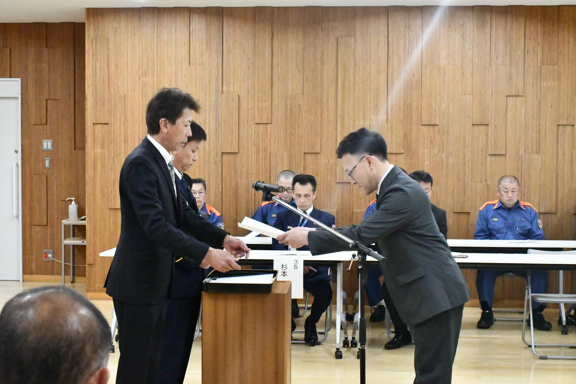 消防団長が新分団長へ辞令を交付している様子