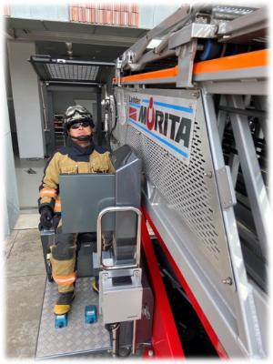 サングラスを着用した消防職員がはしご車を操作している写真