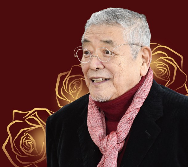 木更津市出身の故中尾彬氏のカラー写真。ピンクのスカーフをつけ、眼鏡をかけてにこやかに微笑んでいます