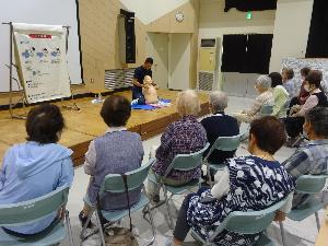 学級生が、救急隊員から胸骨圧迫とAED操作の仕方を教わっている様子。