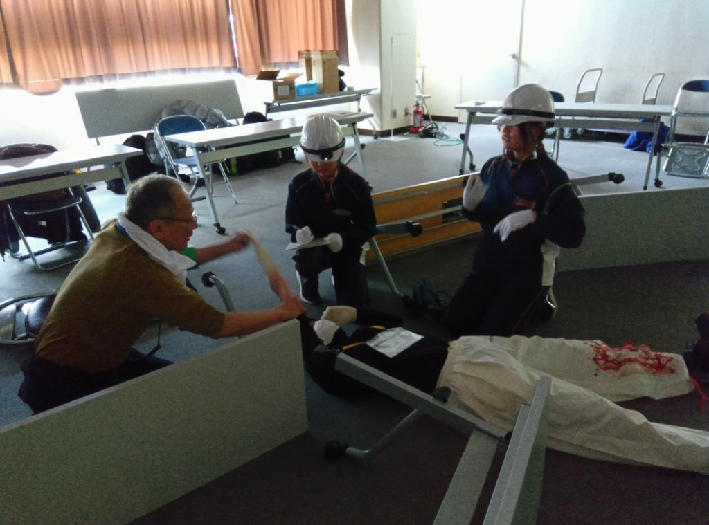 地震災害の現場を想定し、負傷者の応急手当を行っている様子です。