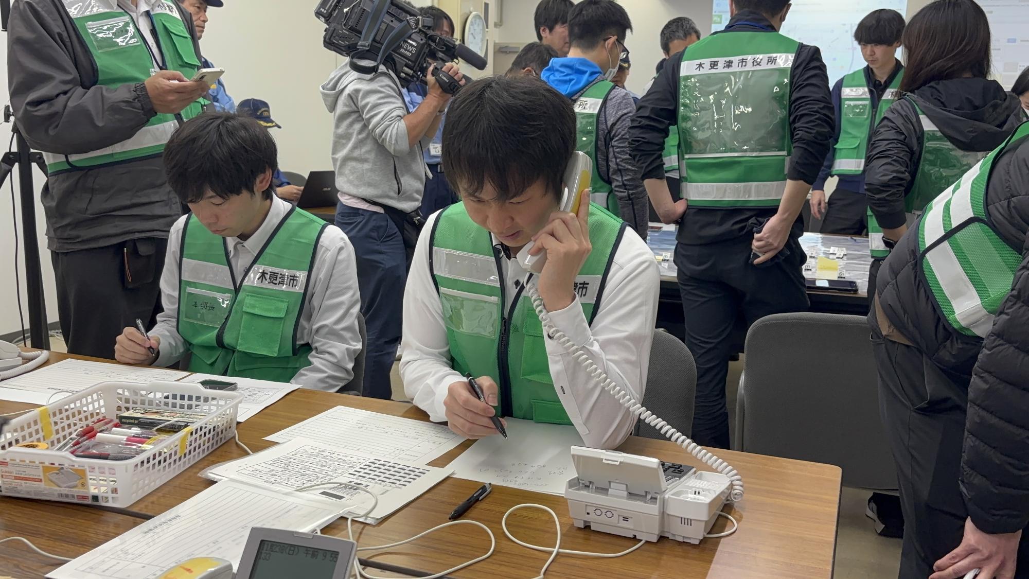 市民からの問い合わせが来ていると仮定し、市職員が電話を受け、紙に記録している様子です。