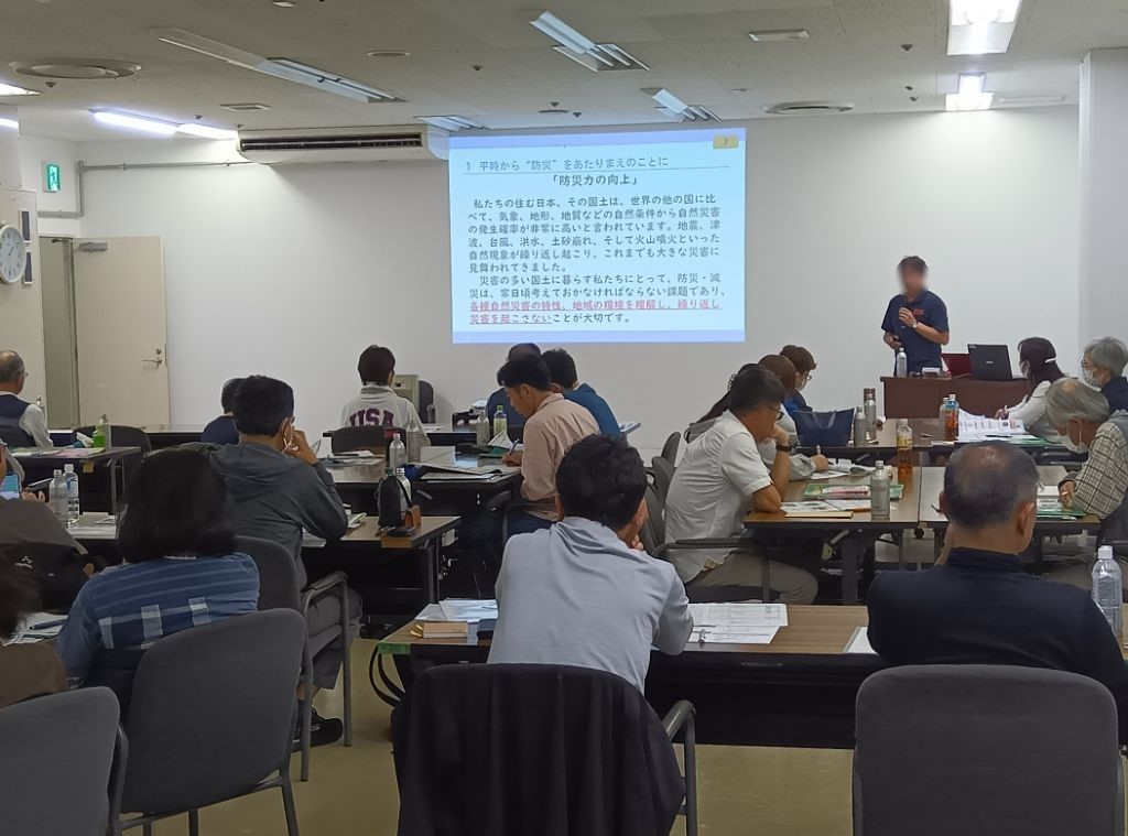 説明者が前に立ち、プロジェクターに移された内容をみて受講している様子