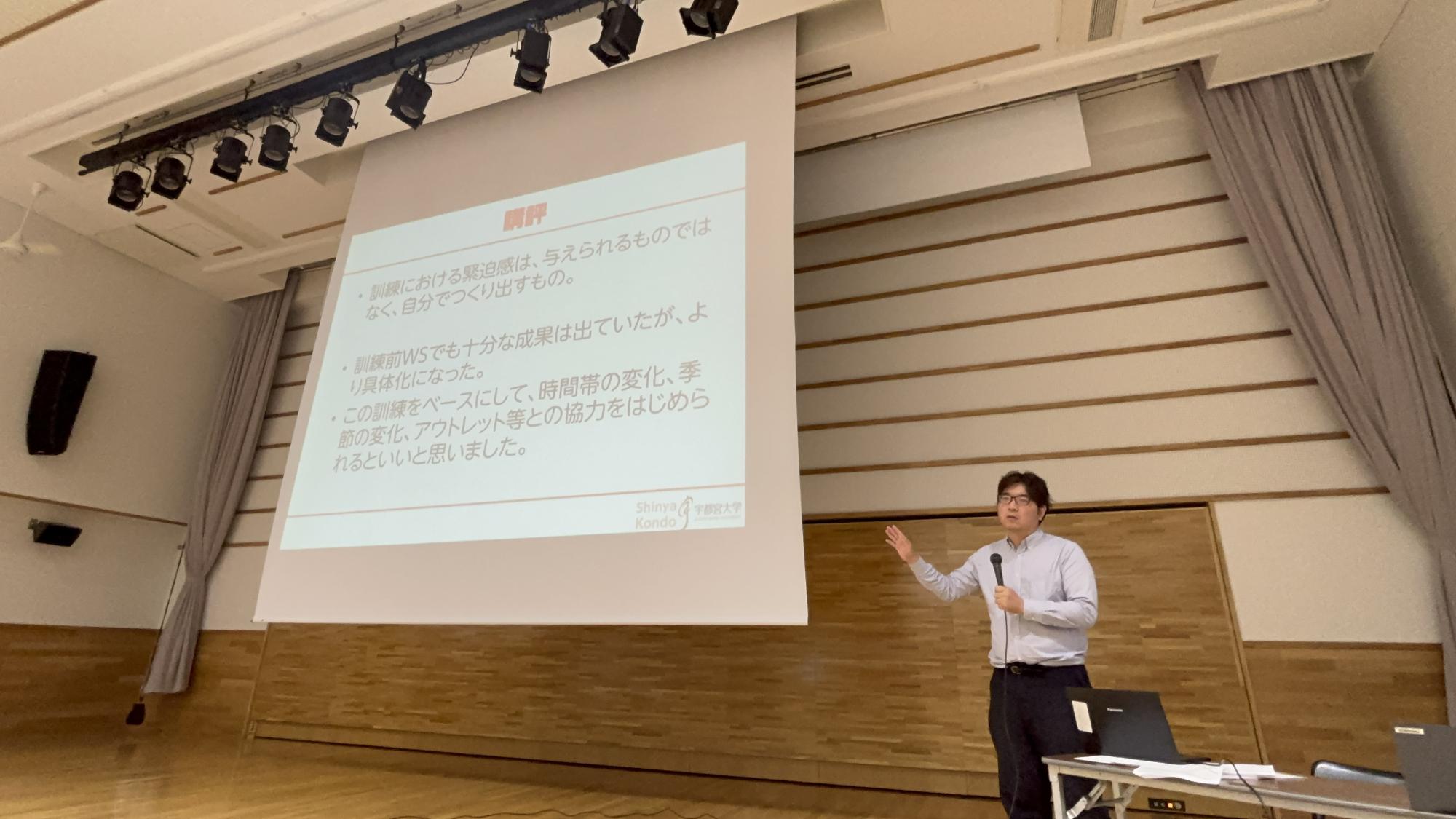 講師による講評の様子です。スクリーンを指さしながら、説明しています。