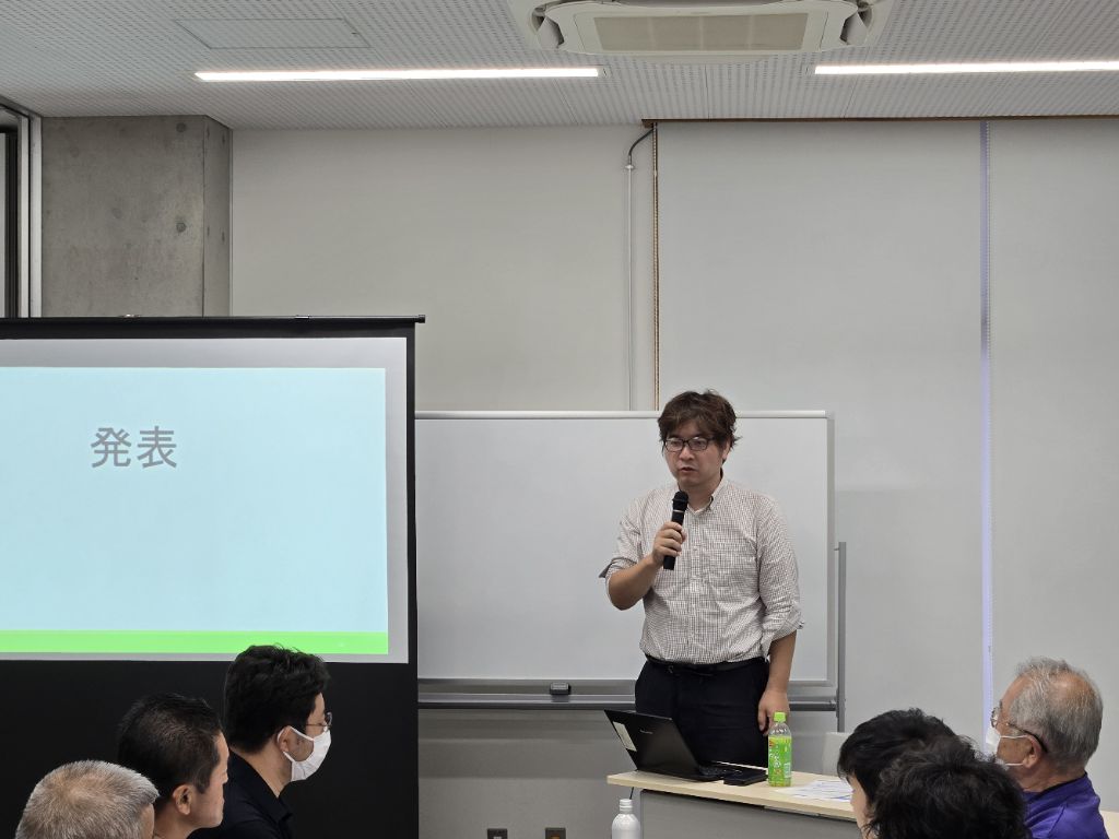 本ワークショップ講師の近藤准教授より、グループ討議の検討結果発表の後に行われた講評の様子です。マイクを持って話しています。