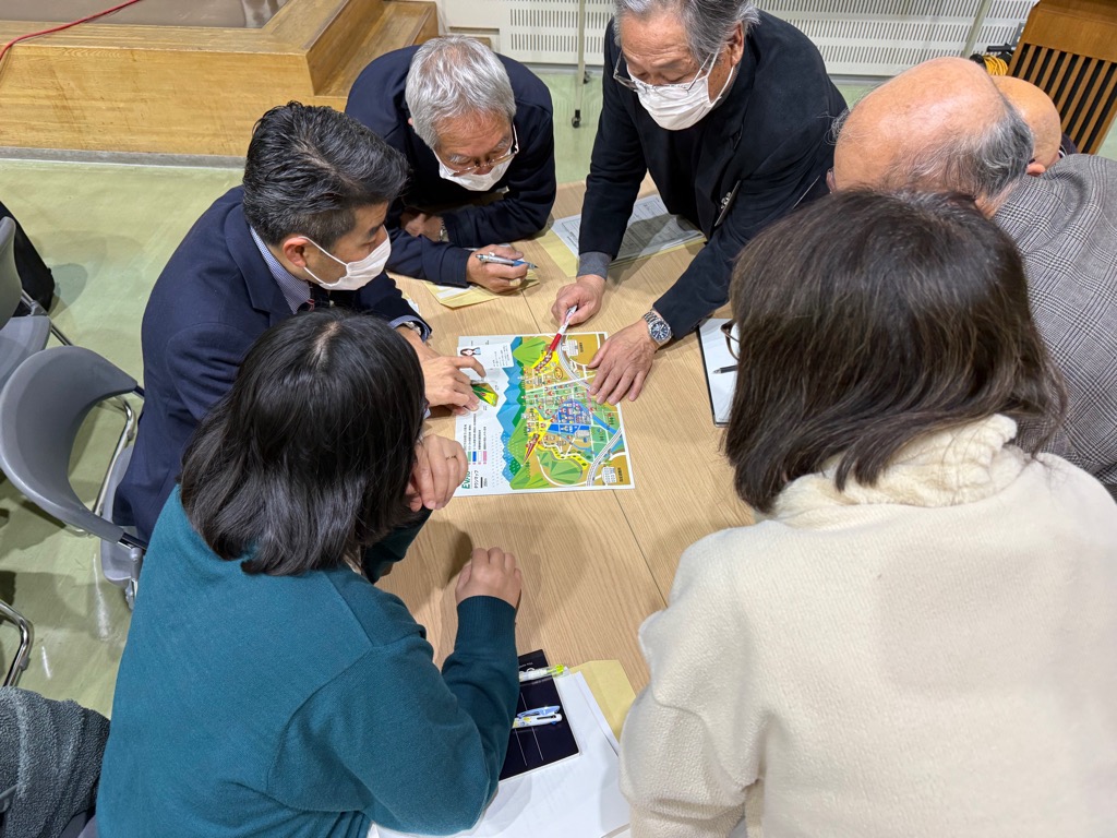 カードゲームタイプの防災教育教材を用いて、災害時の避難行動を疑似体験できるワークショップで、災害時にどのように動くかを考えている参加者の様子になります。