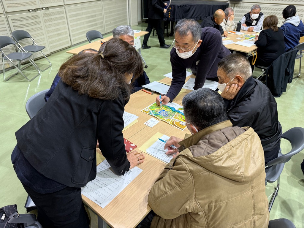 カードゲームタイプの防災教育教材を用いて、災害時の避難行動を疑似体験できるワークショップで、災害時の避難ルートについて話し合っている参加者の様子になります。